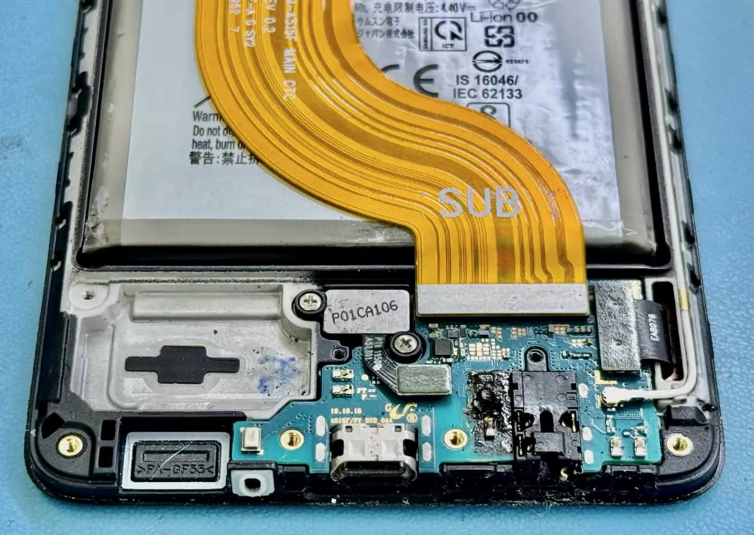 An opened phone showing its logic board and orange ribbon cable after liquid ingress
